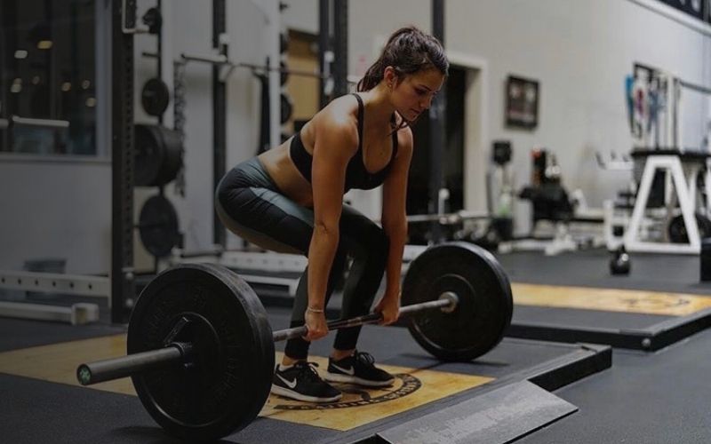 Woman at gym using a barbell