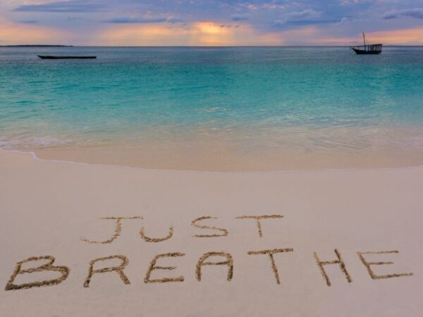 "Just Breath" written in the sand on the beach