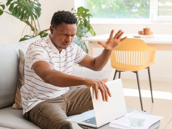 Stressed African-American Man with Laptop At Home