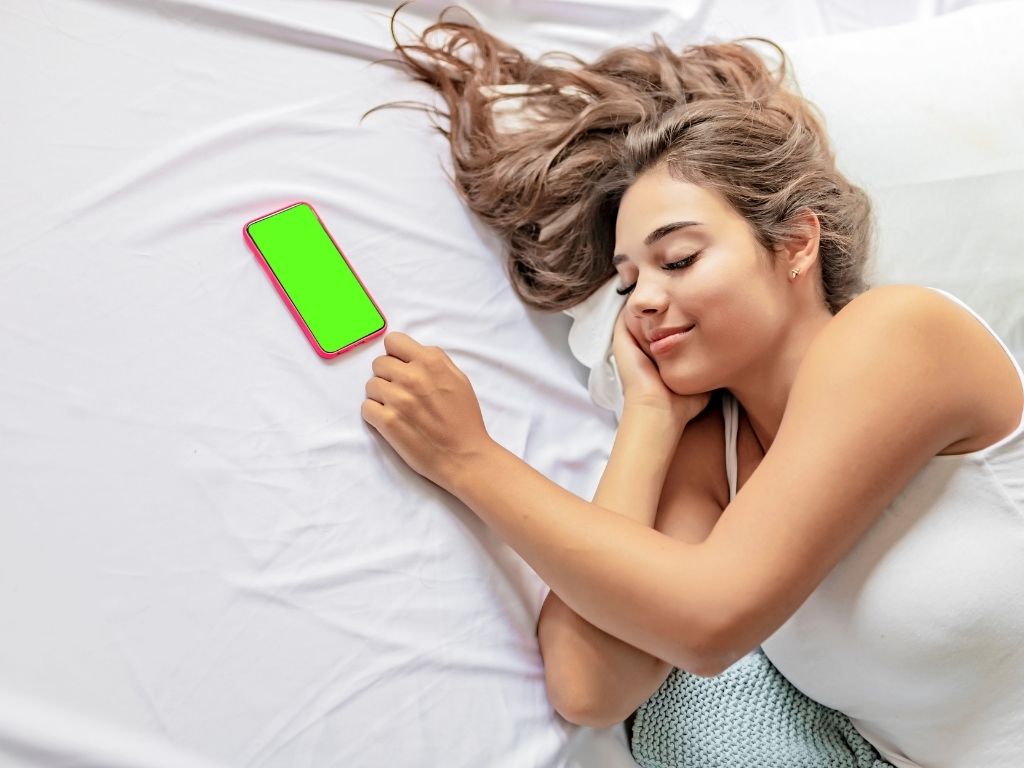 Beautiful woman laying in bed with iphone